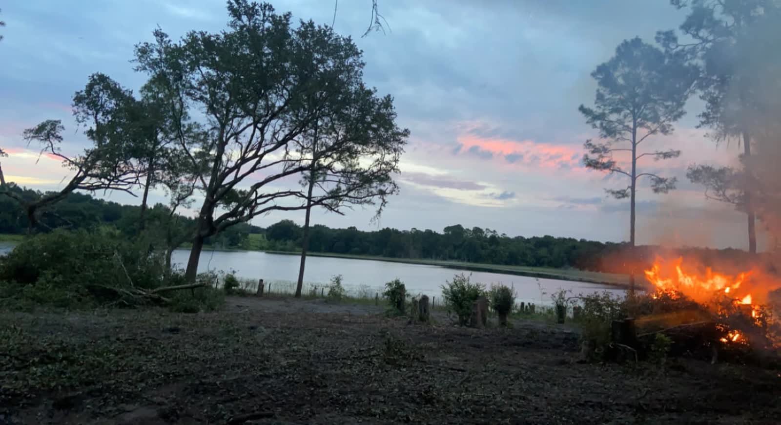 Controlled brush burn at dusk near a Central Florida lake, part of a land-clearing debris cleanup